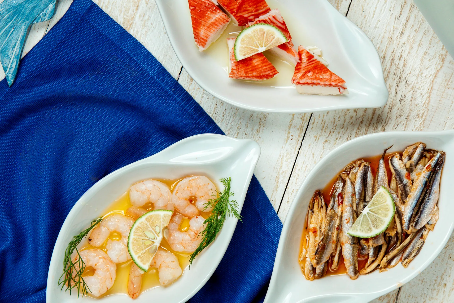 Piatti di gamberi, salmone e acciughe con limone su un tavolo di legno: progetto Brisas Fish Bar di FV Digital Agency