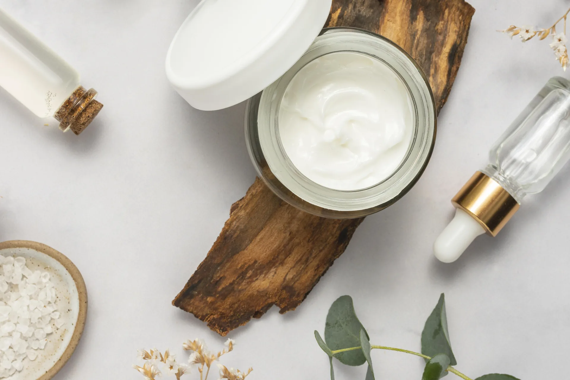 Creme, sali e oli cosmetici su fondo chiaro con elementi naturali: progetto D-Stillate di FV Digital Agency