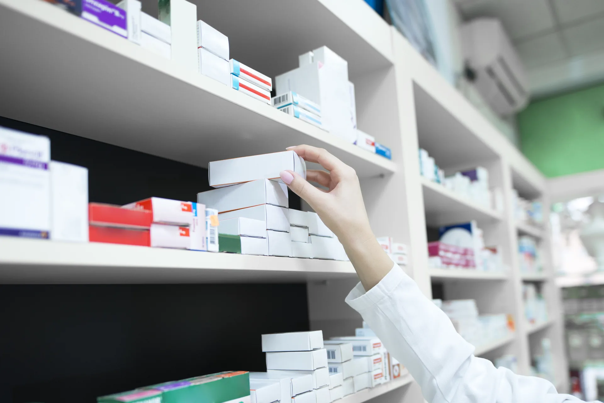 Farmacista che prende una confezione di medicinale da uno scaffale: progetto Farmacia Florio di FV Digital Agency