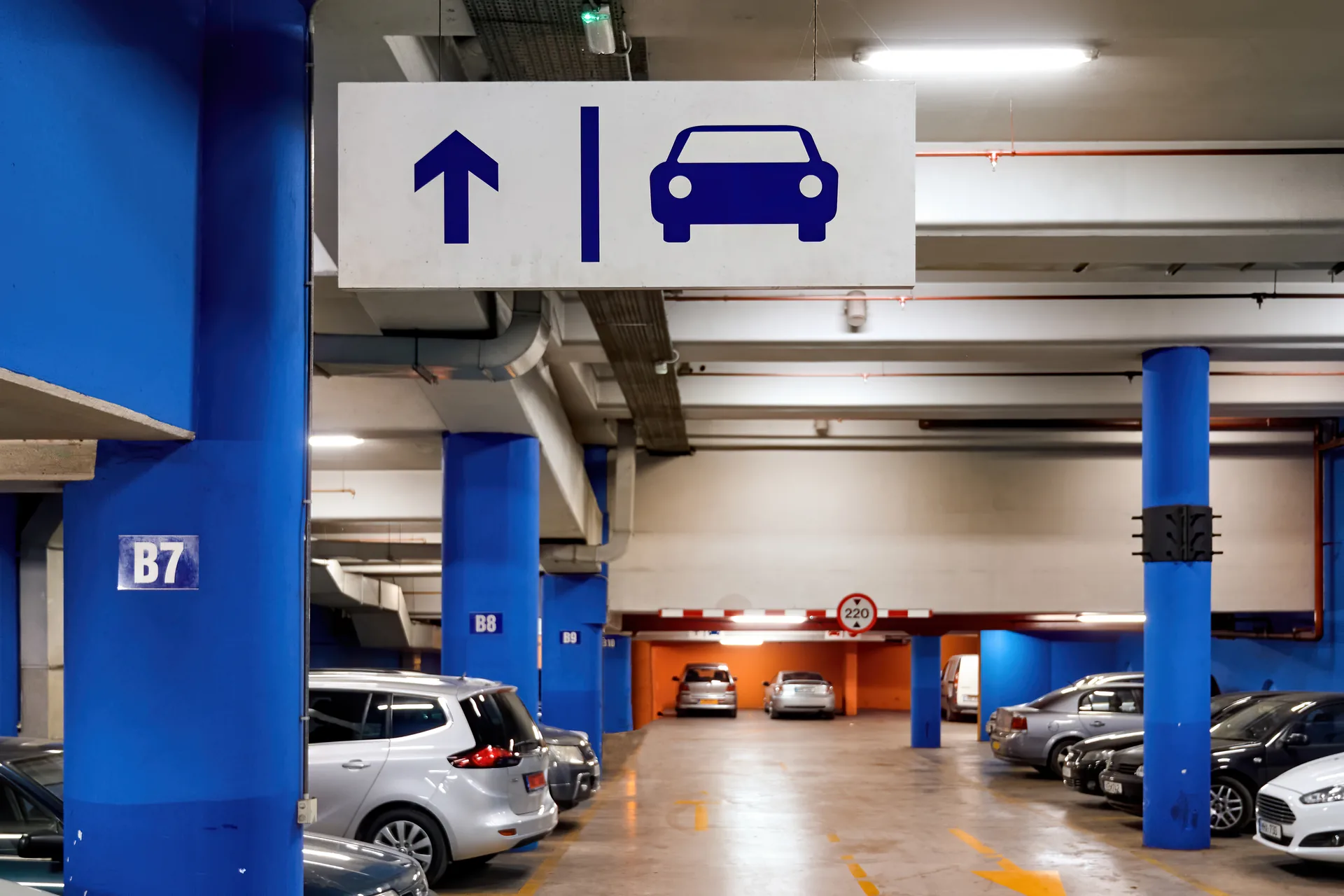 Parcheggio coperto con auto, pilastri blu e segnaletica: progetto Gran Garage Tosti di FV Digital Agency