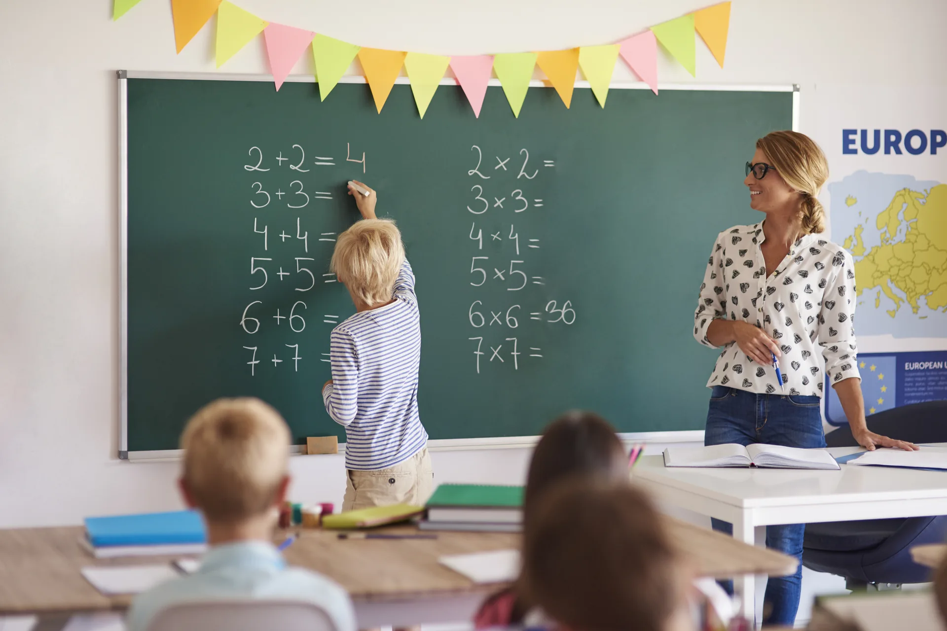 Bambino alla lavagna durante una lezione di matematica con l'insegnante: progetto Istituto Rossini di FV Digital Agency