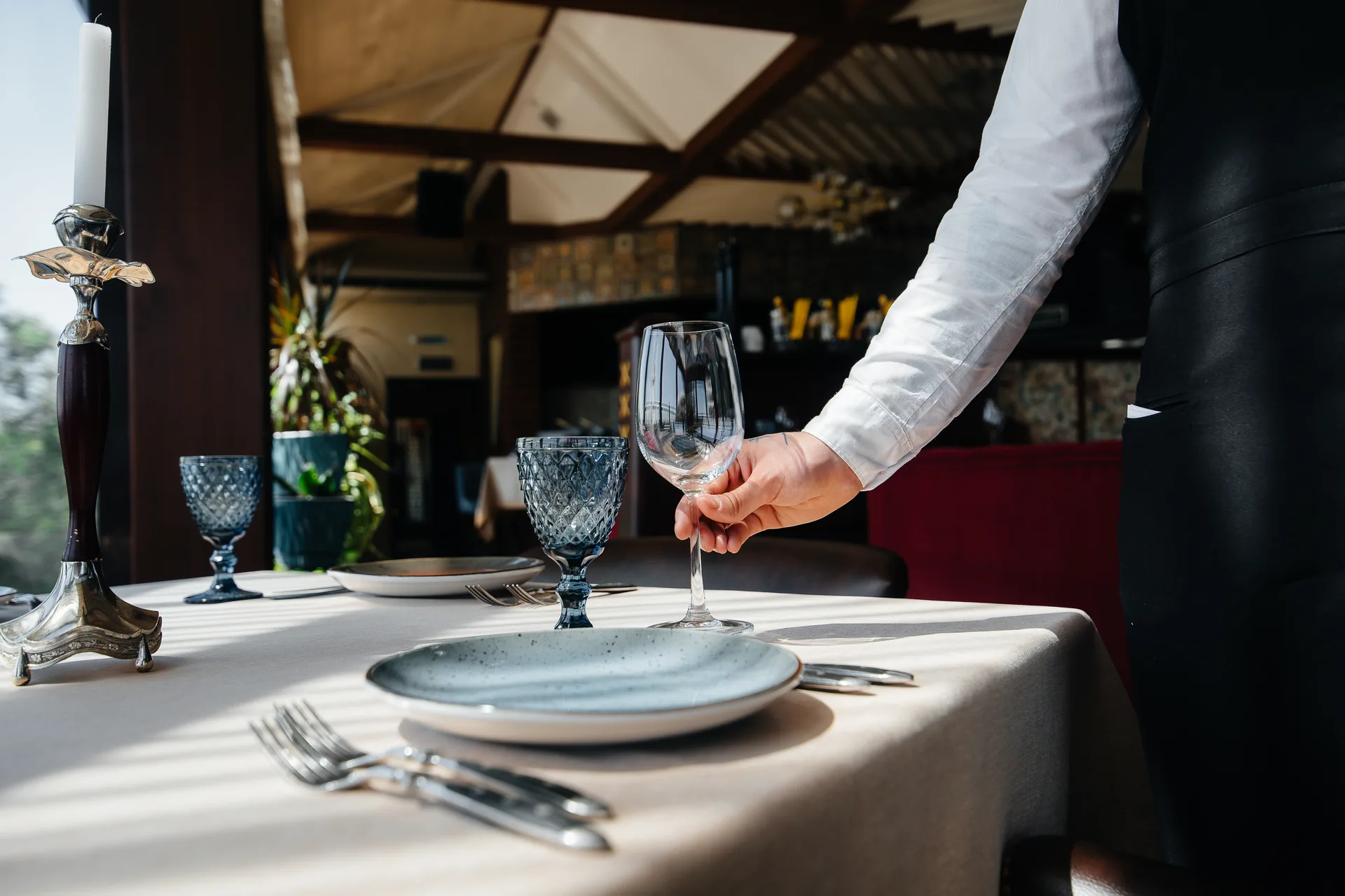 Cameriere che sistema un calice su un tavolo di ristorante elegante: progetto L’Antico Arco di FV Digital Agency