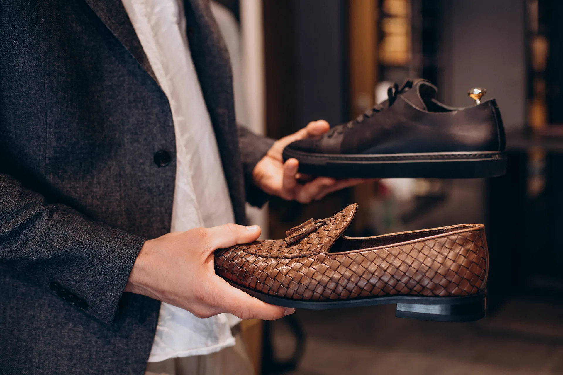 Mani che mostrano due scarpe da uomo in pelle, una stringata e un mocassino intrecciato: progetto Mario Spatarella di FV Digital Agency