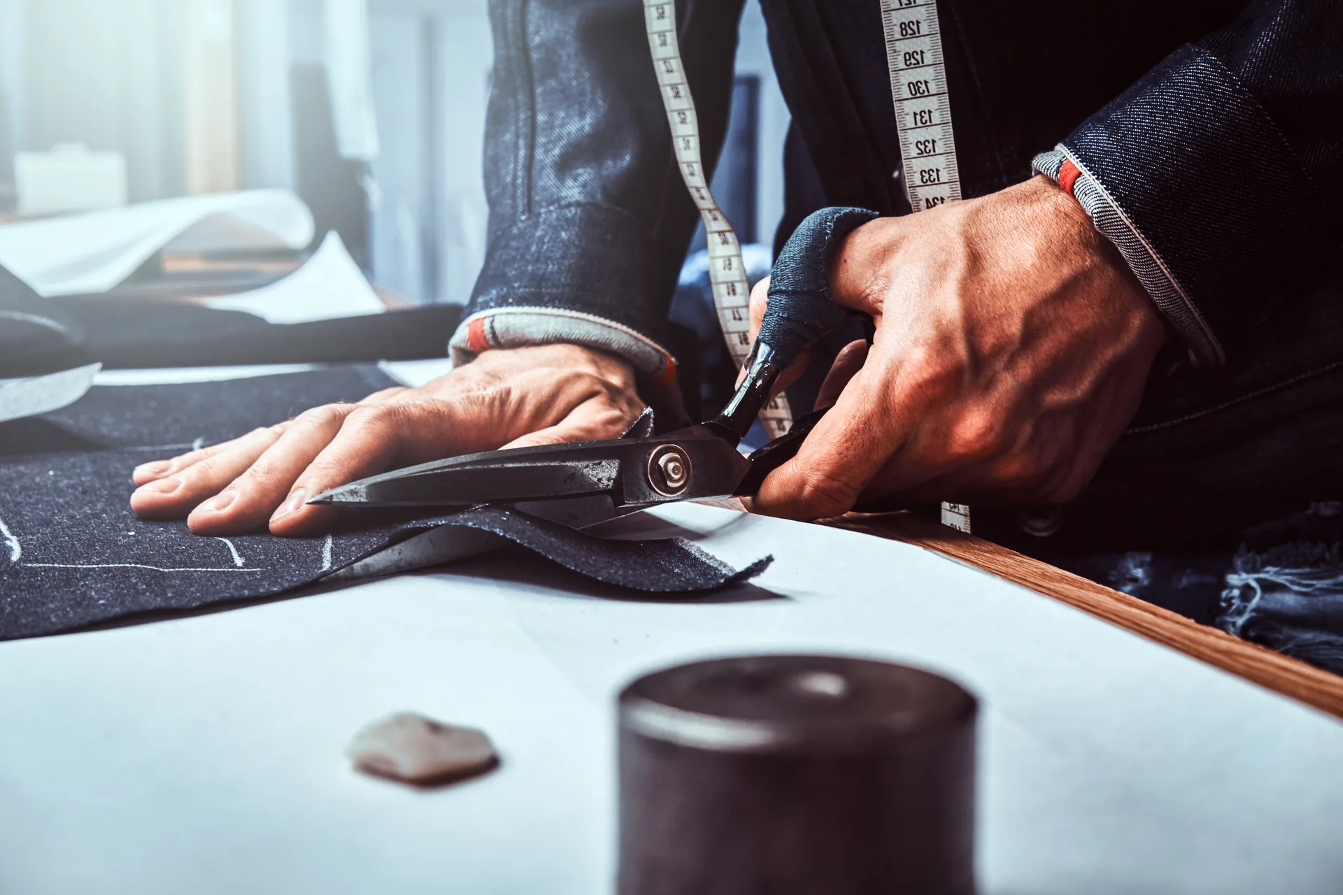 Sarto che taglia un tessuto denim con le forbici: progetto Mr. Cucito Franchising di FV Digital Agency