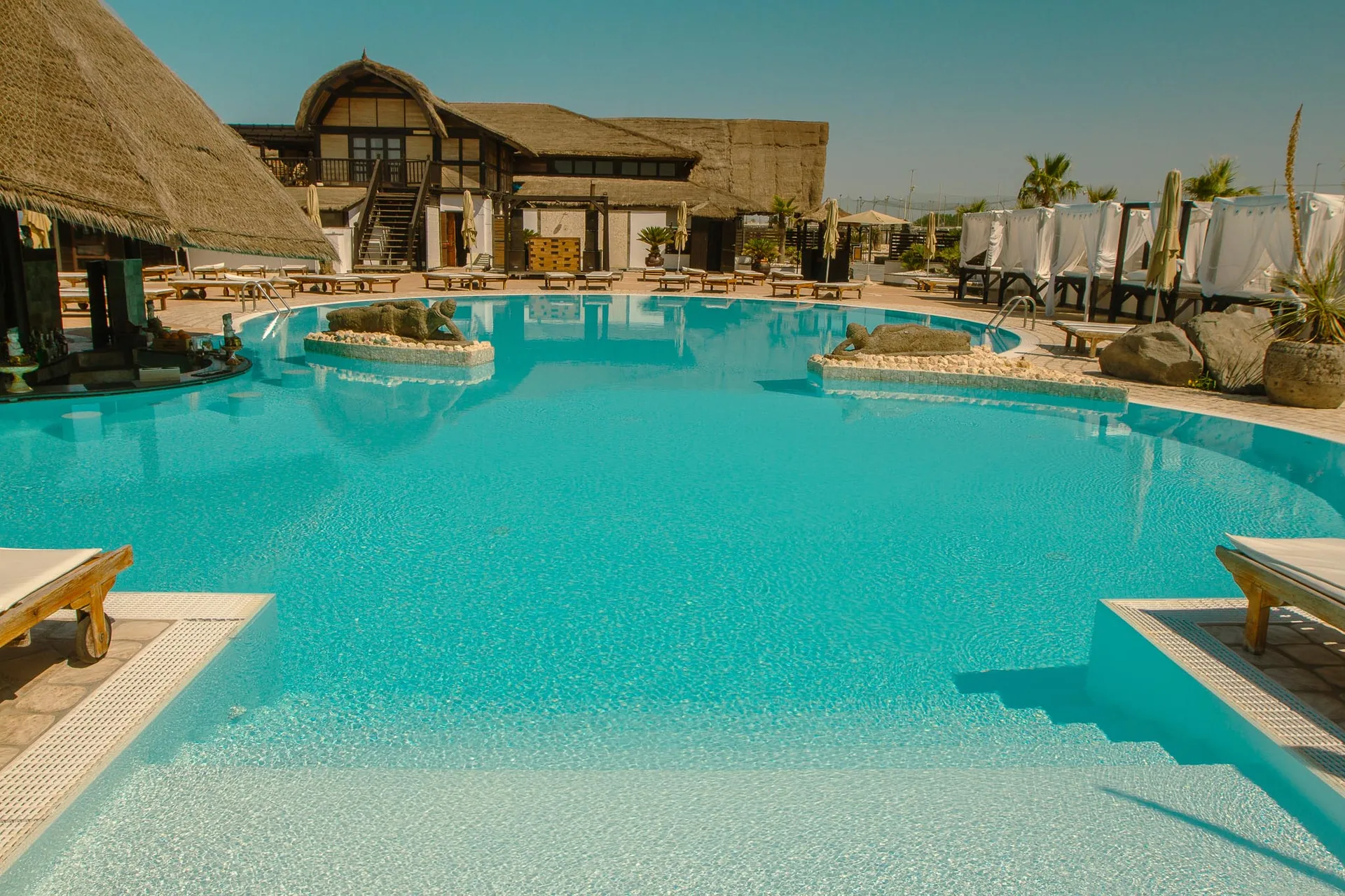 Rama Beach Cafè: case study · Brand Identity, Siti Web Corporate | FV Digital Agency Resort sul mare con piscina turchese e capanne in paglia: progetto Rama Beach Cafè di FV Digital Agency