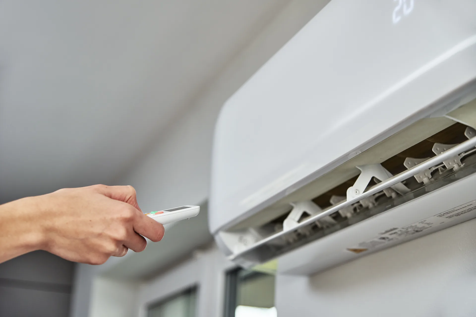 Mano che regola la temperatura di un climatizzatore a muro: progetto Termotek di FV Digital Agency